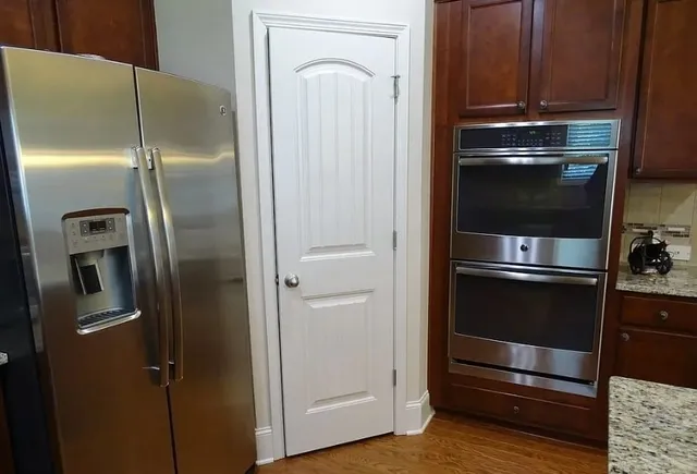 a kitchen with a refrigerator and wooden floor
