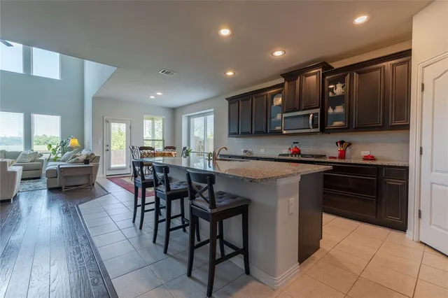 a kitchen with stainless steel appliances granite countertop a stove top oven a sink dishwasher a dining table and chairs with wooden floor