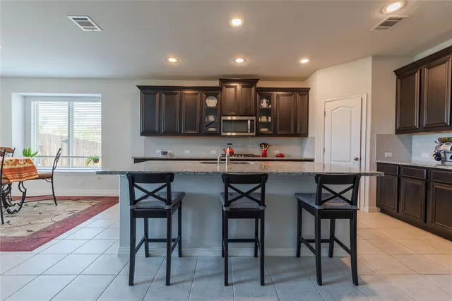 a kitchen with stainless steel appliances kitchen island granite countertop a stove a sink a dining table and chairs