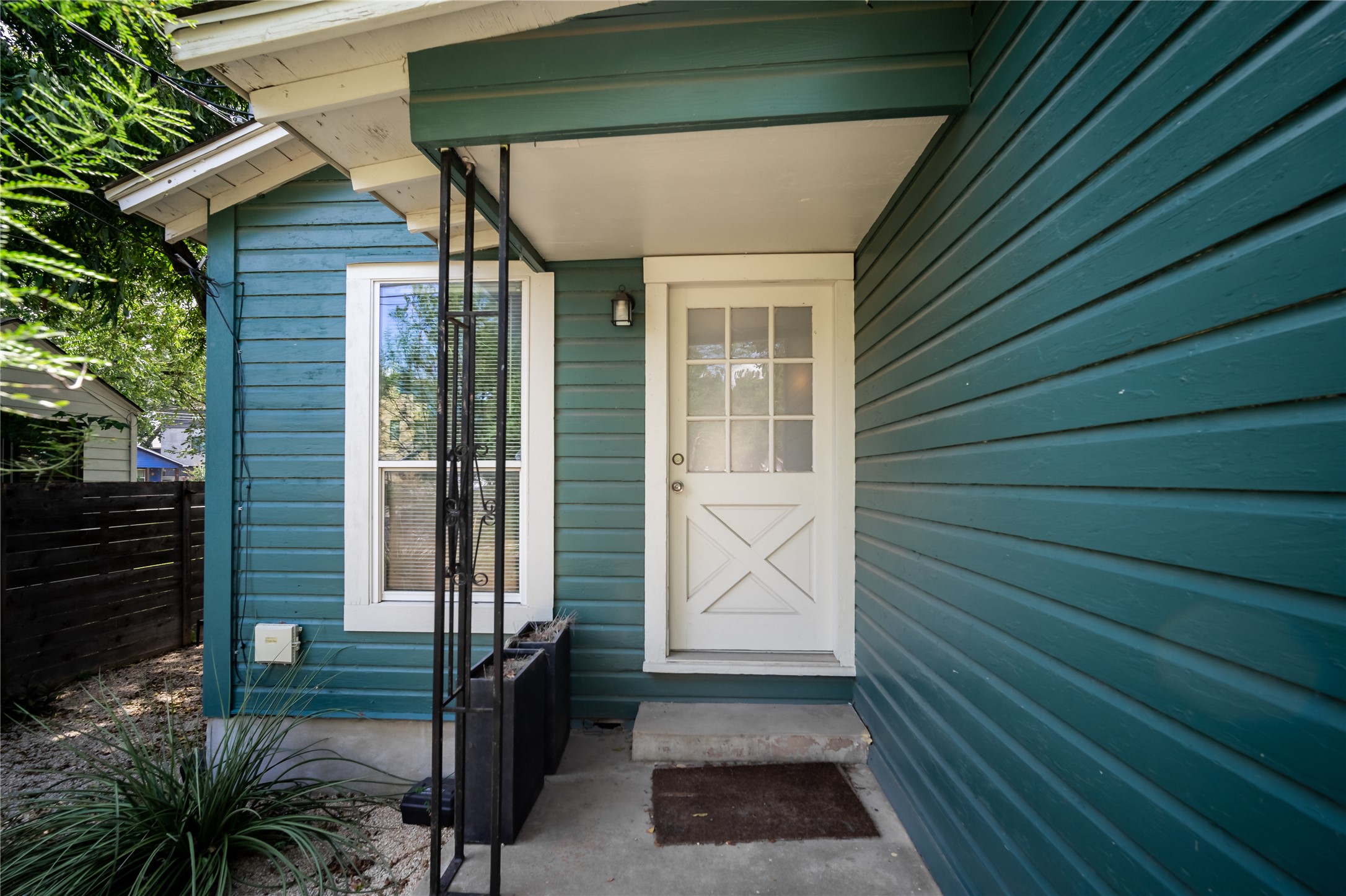 719 Springdale Road Austin, TX 78702 - Photo 6 of 17 A welcoming entry with a crisp white door contrasts against the serene teal siding, offering a cozy and inviting approach.