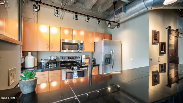 a kitchen with stainless steel appliances granite countertop a refrigerator a stove and a sink with wooden floor