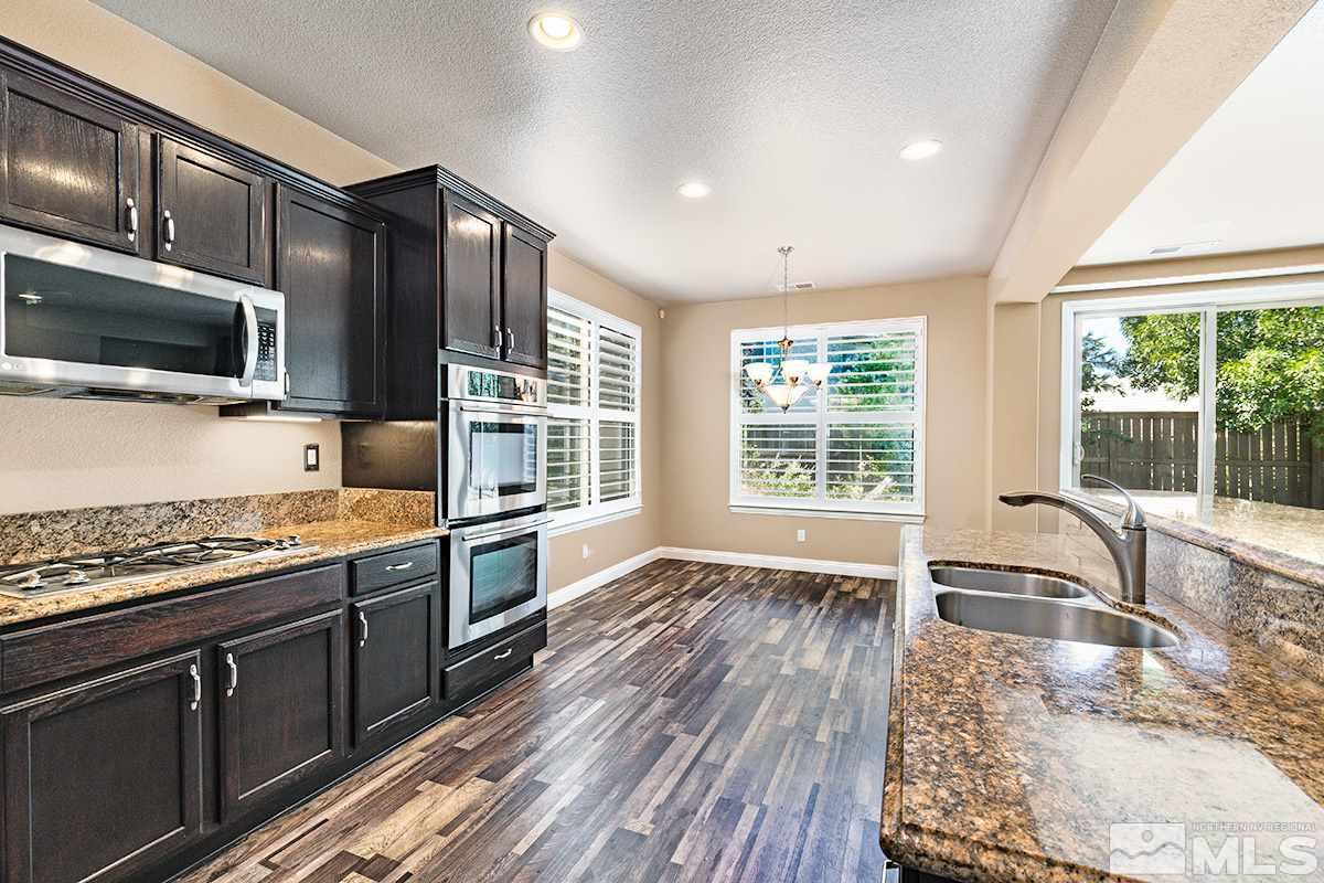 14085 Winners Cup Drive Reno, NV 89521 - Photo 3 of 20 a kitchen with stainless steel appliances granite countertop wooden cabinets a stove top oven a sink and dishwasher next to a window