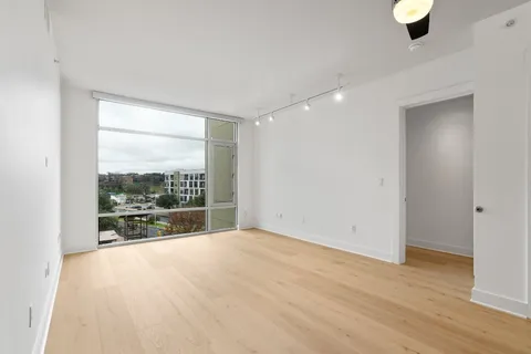 an empty room with floor to ceiling window and wooden floor