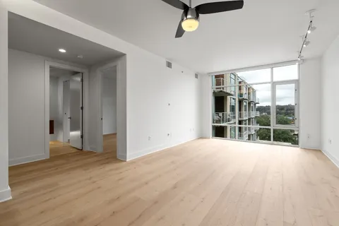 a view of an empty room with a window and wooden floor