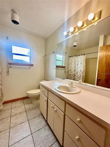 a spacious bathroom with a granite countertop sink a toilet and a mirror