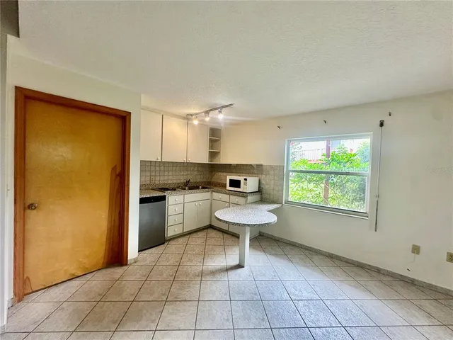 a view of an empty room and a kitchen