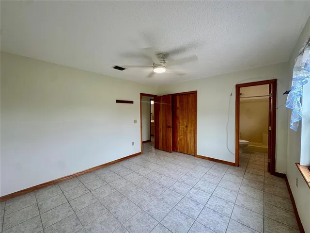 an empty room with closet and a ceiling fan
