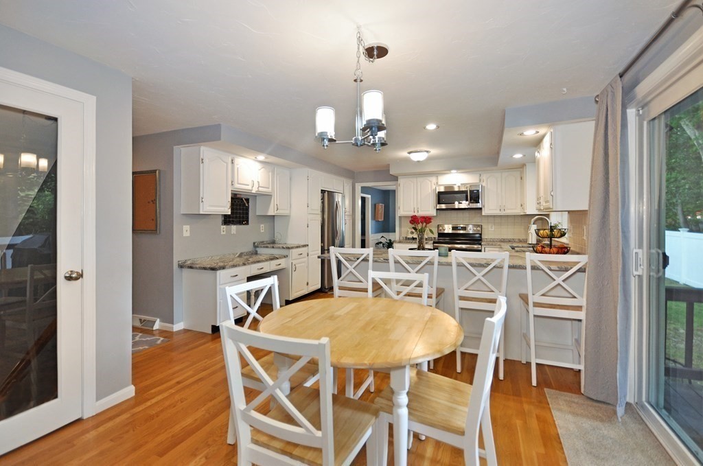 131 Sugar Road Bolton, MA 01740 - Photo 9 of 37 a kitchen with stainless steel appliances kitchen island granite countertop a dining table chairs and sink