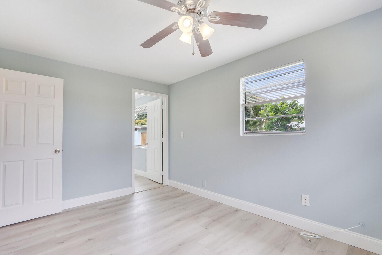 3852 Gull Road Palm Beach Gardens, FL 33410 - Photo 15 of 30 an empty room with wooden floor chandelier fan and windows