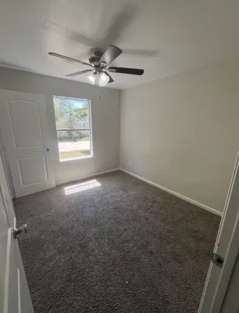 an empty room with windows and fan