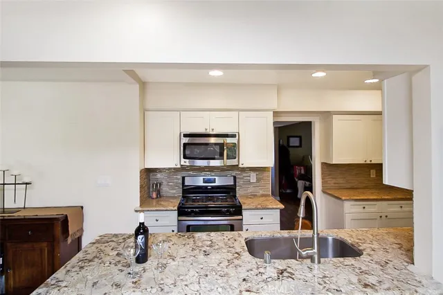 a kitchen with stainless steel appliances kitchen island granite countertop a refrigerator and a stove top oven