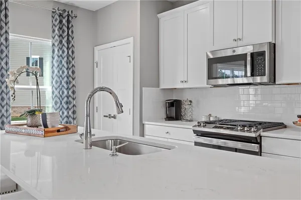 a kitchen with granite countertop a stove a sink and a microwave