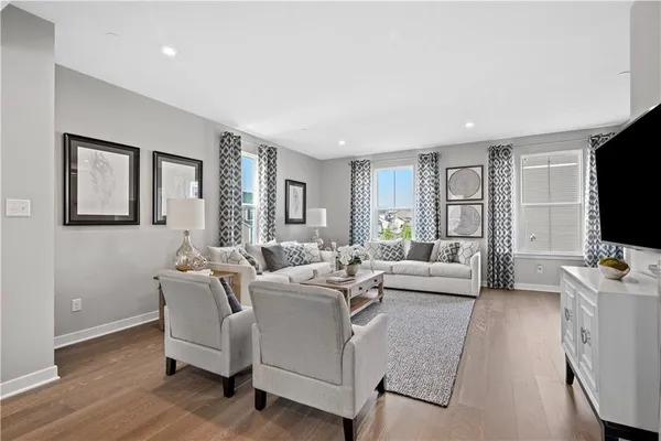 a living room with furniture a flat screen tv and large window