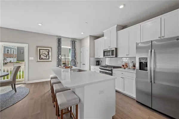 a kitchen with stainless steel appliances a refrigerator a stove a sink a dining table and chairs