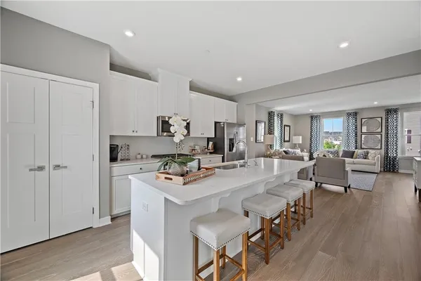 a living room with stainless steel appliances furniture a rug kitchen view and a wooden floor