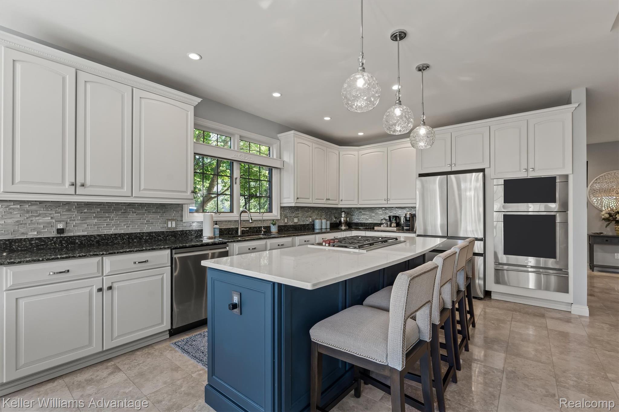 22878 Tree Top Court South Lyon, MI 48178 - Photo 10 of 75 Contemporary kitchen featuring a large center island with seating, stainless steel appliances, white cabinetry, and granite countertops