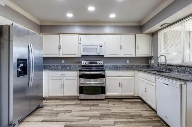 a kitchen with cabinets stainless steel appliances and a window