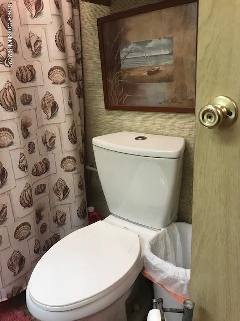 470 Baker Road Merritt Island, FL 32953 - Photo 12 of 21 a white toilet sitting next to a shower curtain