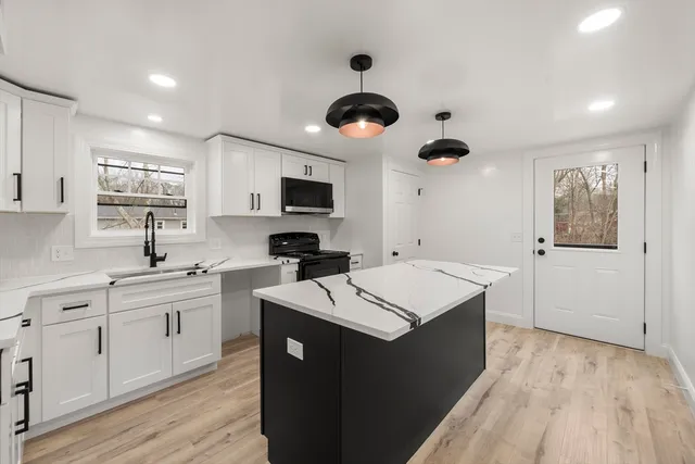 a kitchen with a sink a counter space appliances and cabinets