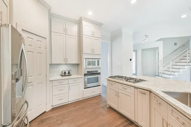 a kitchen with stainless steel appliances a stove a refrigerator and white cabinets