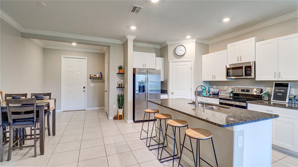 31632 Blue Passing Loop Wesley Chapel, FL 33545 - Photo 13 of 48 a kitchen with stainless steel appliances granite countertop a stove a sink a microwave a refrigerator and cabinets