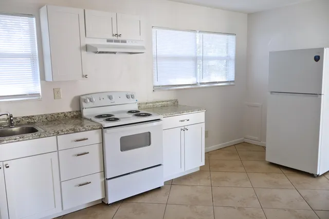 a kitchen with granite countertop white cabinets and white appliances