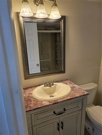 a bathroom with a granite countertop sink a toilet and a mirror