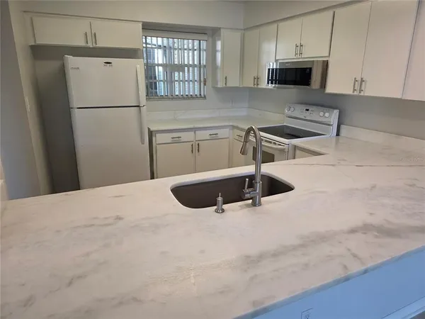 a kitchen with stainless steel appliances a refrigerator a sink a stove a microwave and cabinets