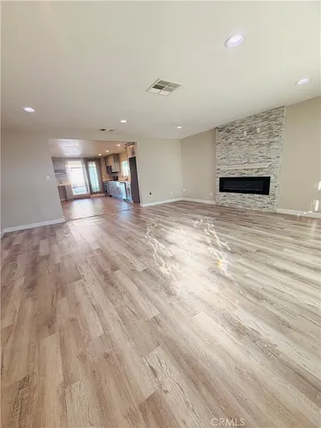 an empty room with wooden floor and kitchen view