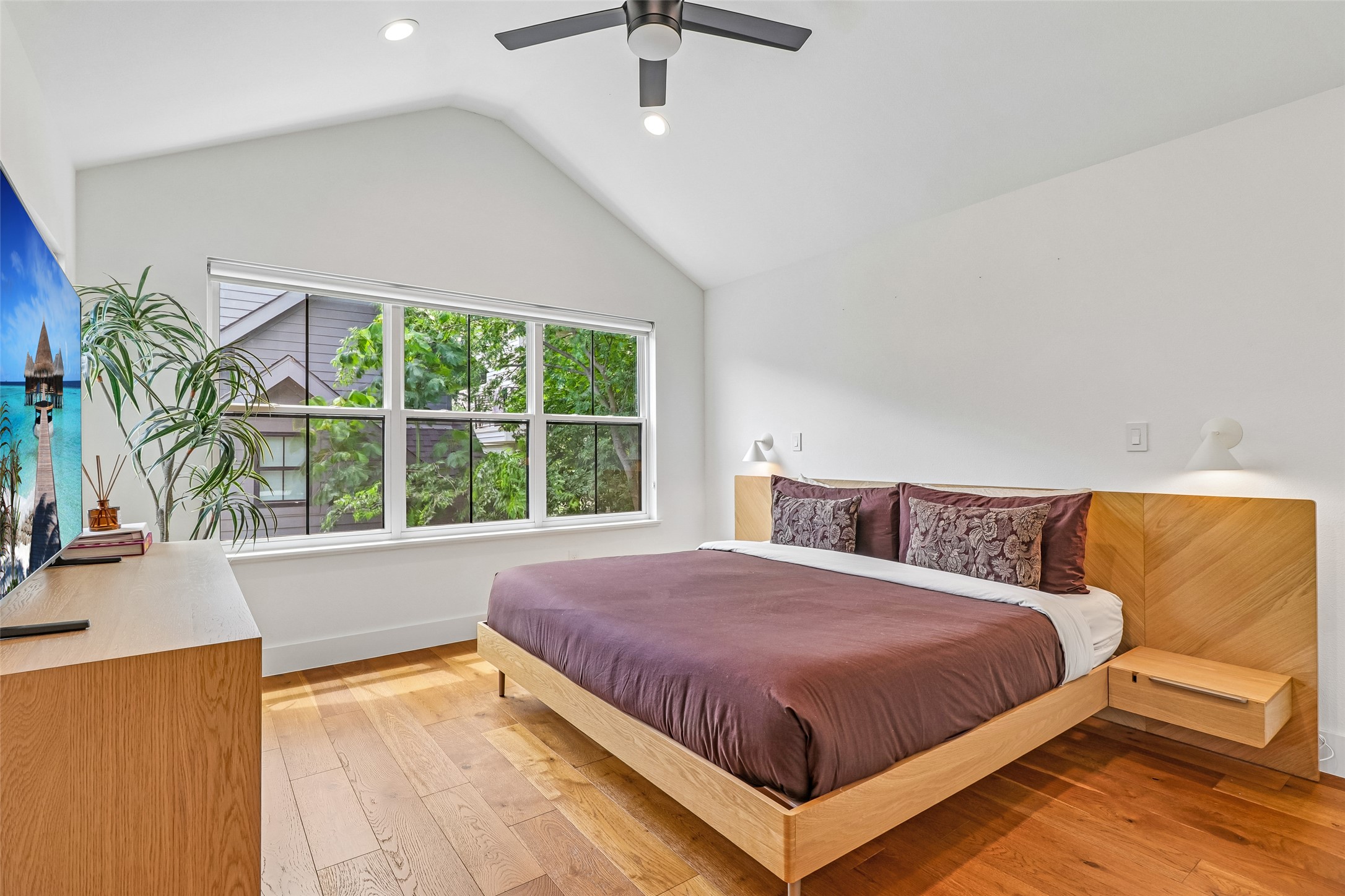 1706 Perez Street, Unit 1 Austin, TX 78721 - Photo 24 of 36 Vast windows illuminate this primary bedroom, showcasing gleaming hardwood floors and a striking vaulted ceiling.