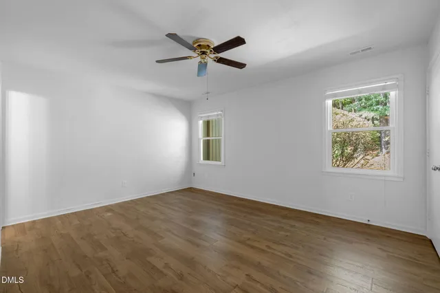 a view of a big room with wooden floor and windows