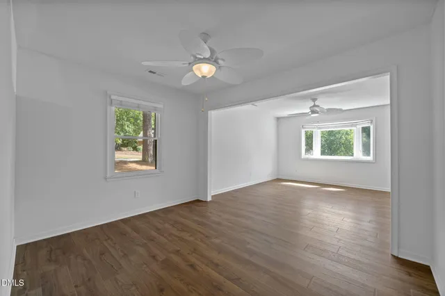 a view of an empty room with a window and wooden floor