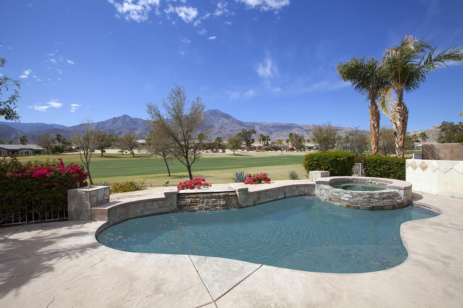 a view of a swimming pool and lounge chairs in the patio