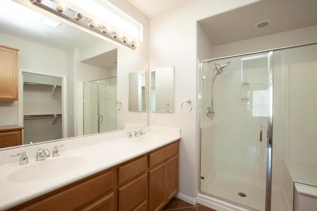 a bathroom with a double vanity sink mirror and shower