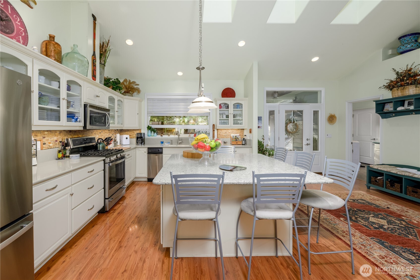 121 Buck Loop Road Sequim, WA 98382 - Photo 13 of 40 a kitchen with stainless steel appliances kitchen island granite countertop a stove top oven a sink a dining table and chairs with wooden floor