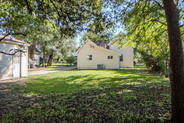 a view of a white house with a big yard and large tree