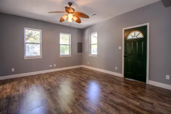 a view of an empty room with wooden floor and a window