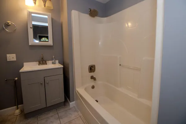a bathroom with a tub sink vanity and mirror