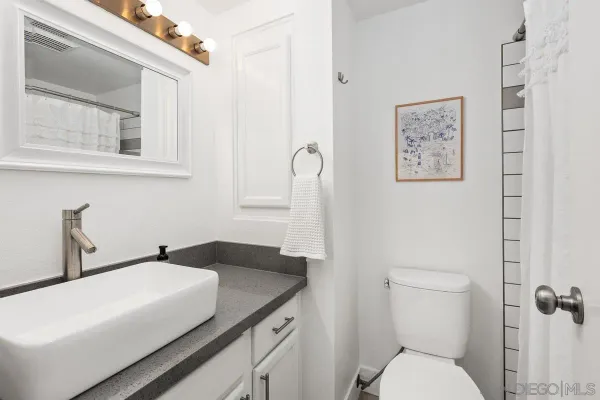 a bathroom with a granite countertop sink a toilet and a mirror