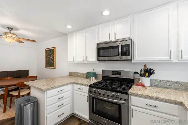 a kitchen with granite countertop white cabinets stainless steel appliances and a counter space