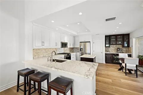 a kitchen with stainless steel appliances kitchen island granite countertop a dining table chairs and white cabinets