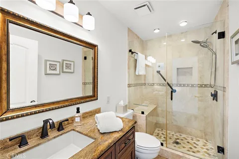 a bathroom with a granite countertop sink toilet a mirror and shower