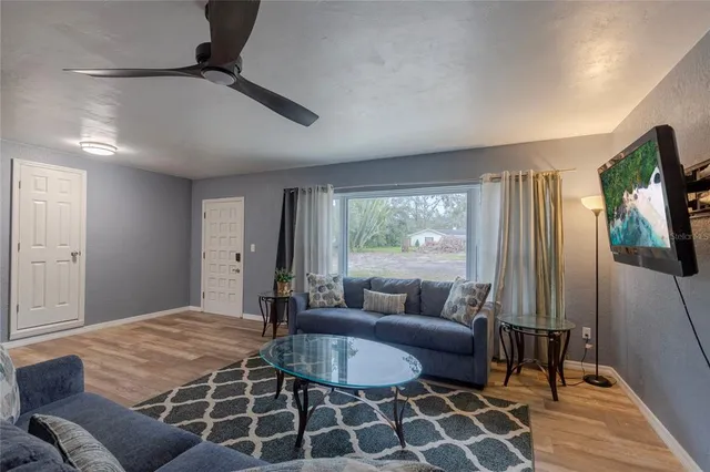 a living room with furniture a flat screen tv and a floor to ceiling window