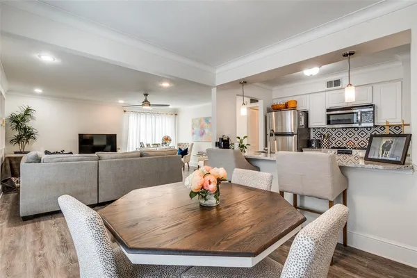 a living room with furniture kitchen view and a wooden floor