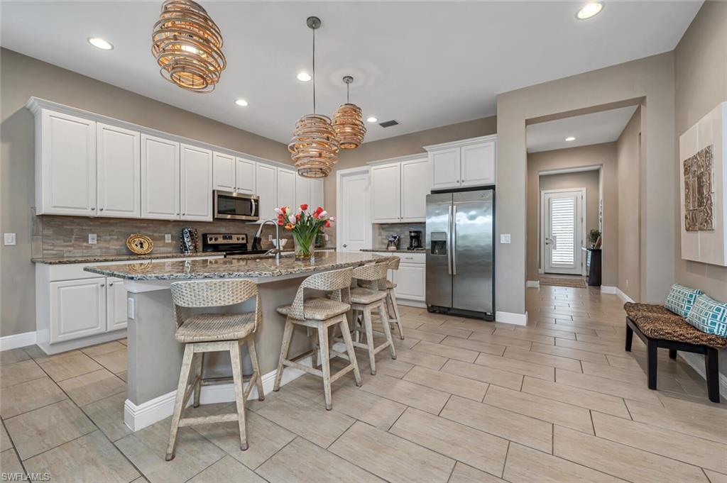 a kitchen with stainless steel appliances granite countertop a stove a refrigerator a microwave oven a sink with a dining table and chairs