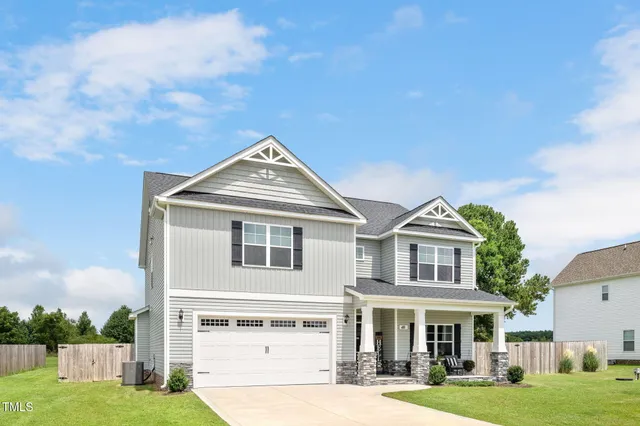 a front view of a residential houses with yard and parking space