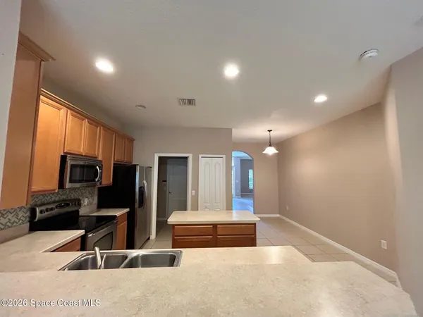 a living room with stainless steel appliances kitchen island granite countertop a refrigerator and a stove top oven