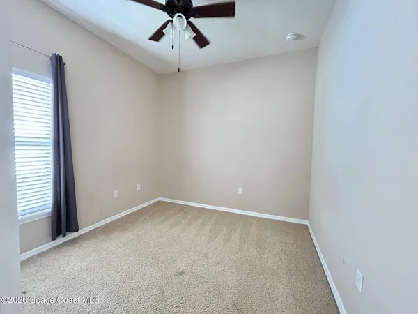 an empty room with a window and a ceiling fan