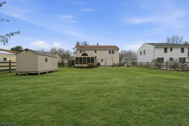 a view of a white house with a big yard and large trees