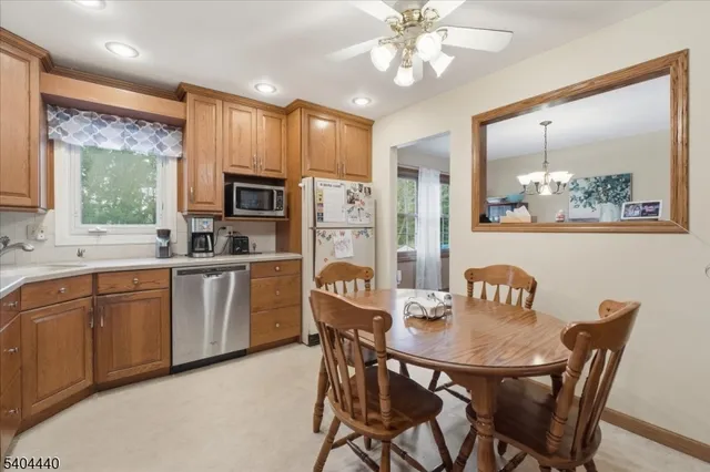 a kitchen with stainless steel appliances granite countertop a dining table chairs refrigerator and microwave